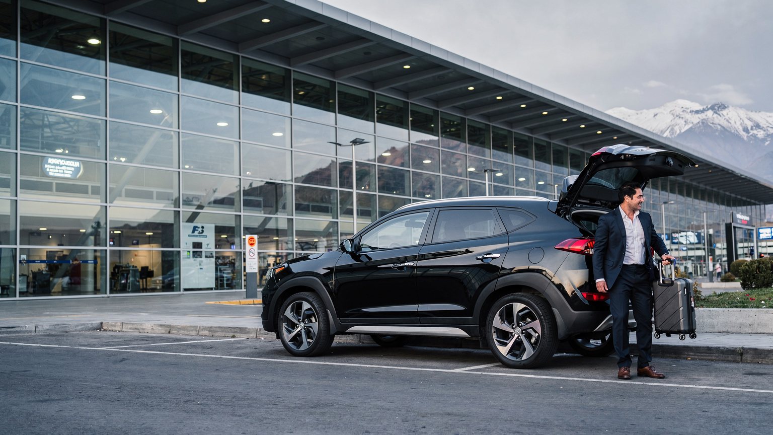 SUV negro estacionado frente al terminal con la cordillera de fondo